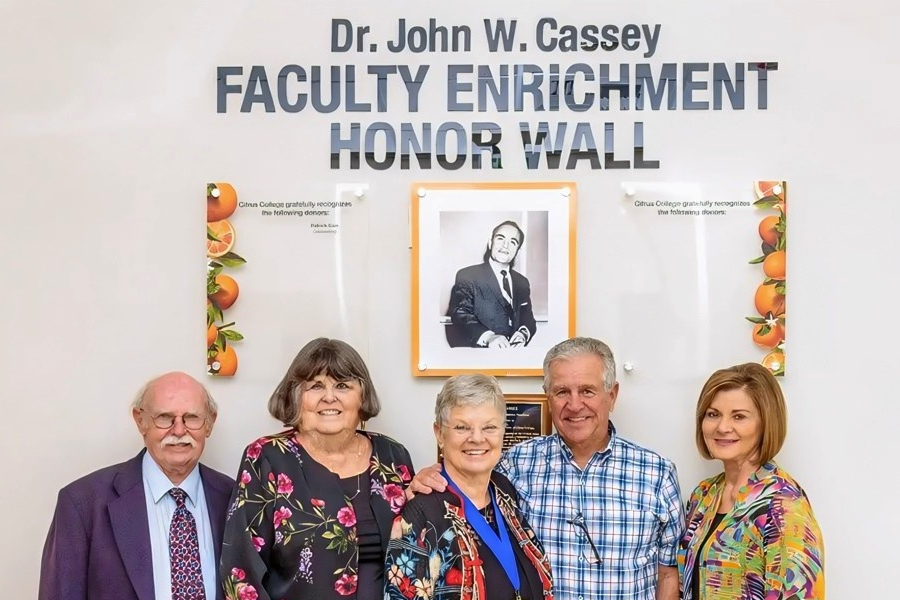 five people stand together in front of the dr. john w. cassey faculty enrichment honor wall at citrus college
