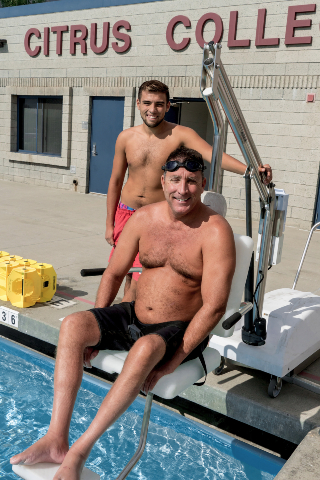 a male KIN 149 aquatics student on the aquatics lift chair with a nearby assistant