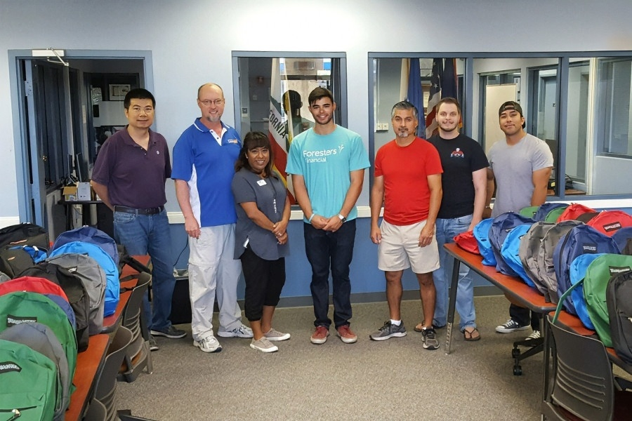 seven citrus college and foresters volunteers stand among rows of backpacks filled with school supplies for student-veterans