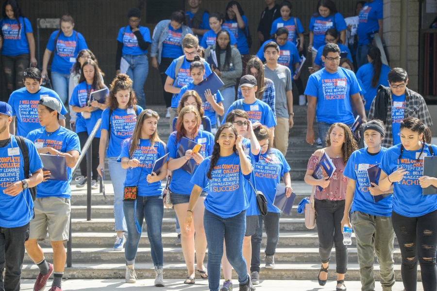 students wearing blue i will complete college shirts walk down campus steps together at welcome day