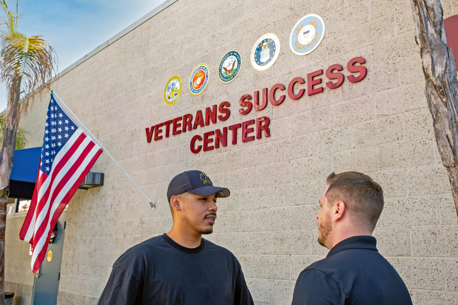 Two student-veterans standing outside the Veterans Success Center with an American flag in the background