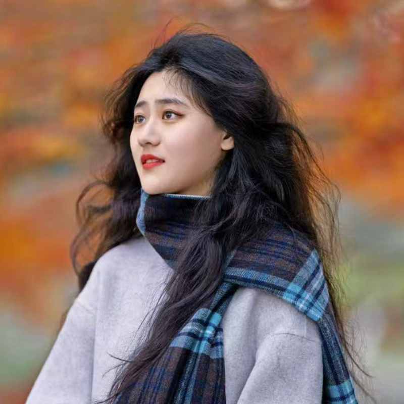headshot of Xinyue Margaret Liang wearing a scarf and sweater outdoors with autumn colors in the background