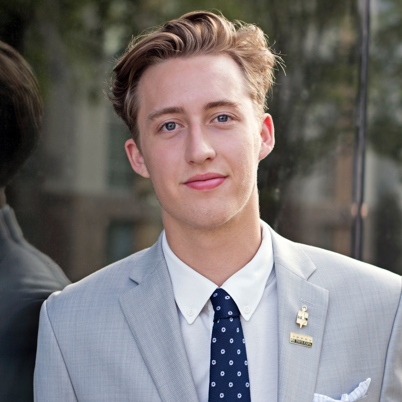 philippe schicker poses outdoors in a light gray suit and tie